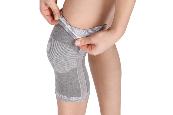 Diz Destek Kolu beyaz arka planda izole edilmiş bir bacak üzerinde. Ortopedik Anatomik Ortopedi. Diz sabitleme, yaralanma ve ağrı için diş telleri. Ortopedi. Ayak ortozu. Diz eklemi bandaj kolu. Elastik Spor