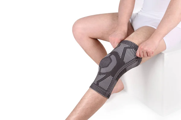 Diz Destek Kolu beyaz arka planda izole edilmiş bir bacak üzerinde. Ortopedik Anatomik Ortopedi. Diz sabitleme, yaralanma ve ağrı için diş telleri. Ortopedi. Ayak ortozu. Diz eklemi bandaj kolu. Elastik Spor