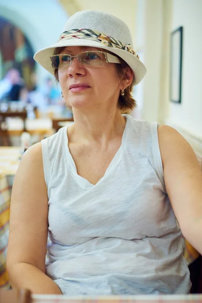 Красивая женщина в шляпе сидит в кофе — стоковое фото
