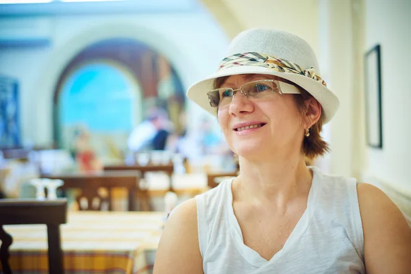 Красивая женщина в шляпе сидит в кофе — стоковое фото