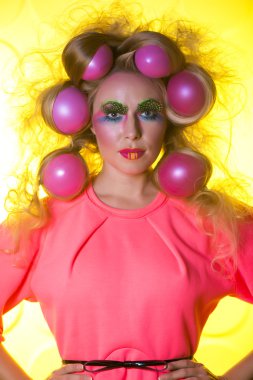 Sarı bir arka plan üzerinde parlak makyaj ve saç topları ile kız