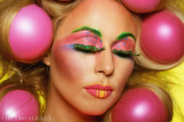 Girl with bright makeup and hair balls on a yellow background — Stock Photo, Image