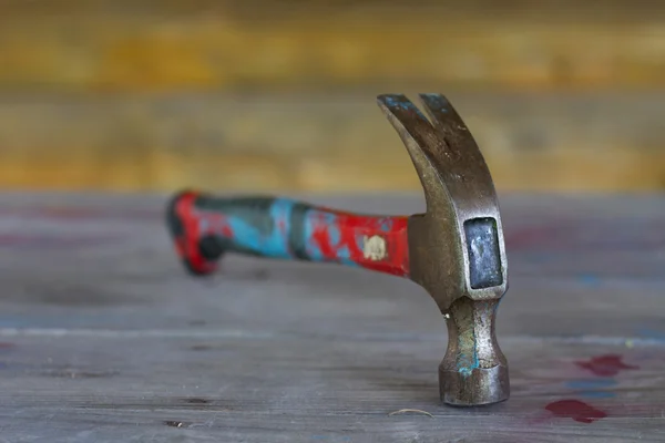 Vecchio martello di ferro colorato su tavolo di legno con macchie di vernice — Foto Stock