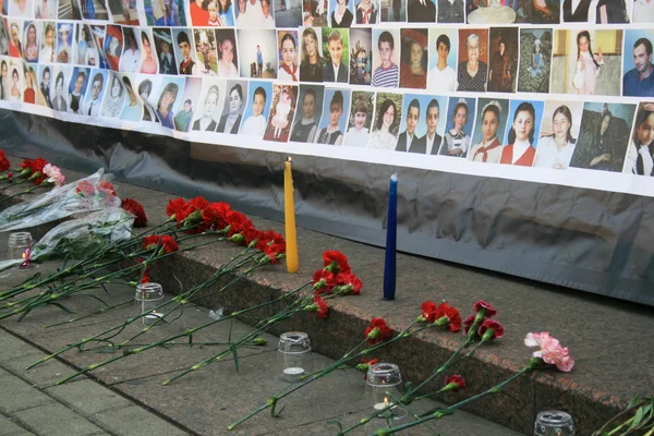 Begrafenis bloemen in de buurt van een poster met foto's van de doden in de kinderen van Beslan. Memorial vergadering in Moskou op de verjaardag van de terroristische aanslag — Stockfoto