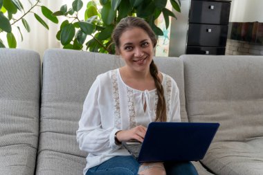 Beyaz bluzlu, kot pantolonlu ve evinde dizüstü bilgisayarı olan güzel bir kız. İş, internet üzerinden iletişim, online alışveriş, gazete okumak.