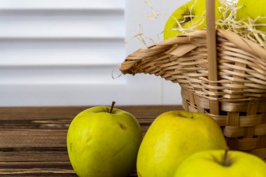 Ahşap arka planda elmalı yeşil elma ve sepet.