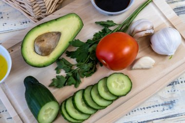 Sebzeler masada ve sepetin içinde, domatesler, salatalıklar, avokado, sarımsak ve zeytinyağı, vejetaryenlik, sağlıklı beslenme