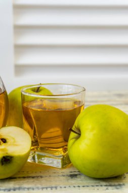 Ahşap zemin üzerinde elma suyu olan yeşil elma ve sürahi.