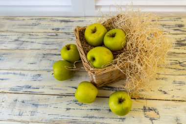 Ahşap arka planda elmalı yeşil elma ve sepet.