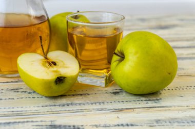 Ahşap zemin üzerinde elma suyu olan yeşil elma ve sürahi.