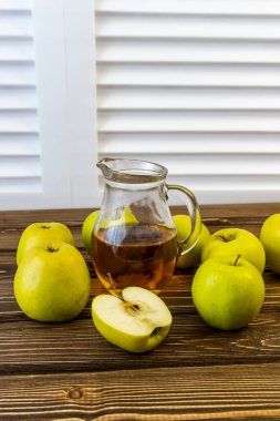 Ahşap zemin üzerinde elma suyu olan yeşil elma ve sürahi.