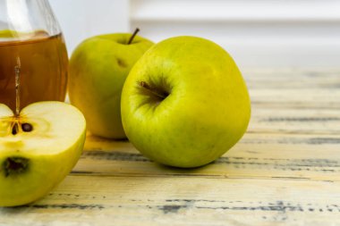 Ahşap zemin üzerinde elma suyu olan yeşil elma ve sürahi.