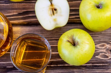 Ahşap zemin üzerinde elma suyu olan yeşil elma ve sürahi.