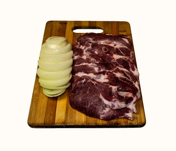 テーブルの上のボード上の豚肉の肉と玉ねぎの形 — ストック写真