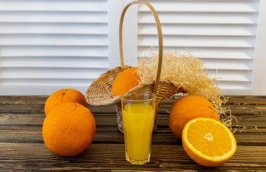 Fotoğraf, Flat Lay Portakallı sepet ve portakal suyu dolu sürahi, ahşap kahverengi arka planda.