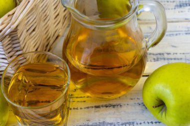 Ahşap zemin üzerinde elma suyu olan yeşil elma ve sürahi.