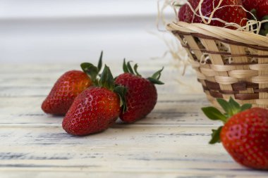 Sepette çilek ve ahşap arka planda masa.