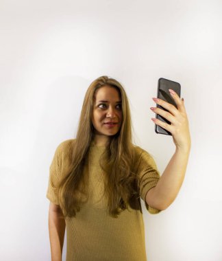 Akıllı telefonlu genç ve güzel bir kadın, bir mesaj yazıyor, selfie çekiyor, iletişim kuruyor.