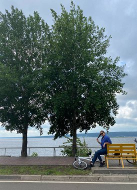 Bir bankta spor yaptıktan sonra dinlenen bisikletli bir kadının fotoğrafı.