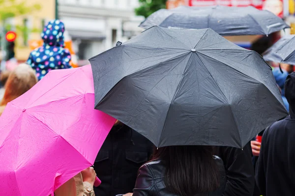 Skara människor med regn paraplyer — Stockfoto