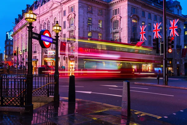 Red double decker bus in motion blur at Piccadilly Circus in London, UK, at night — Stock Photo, Image