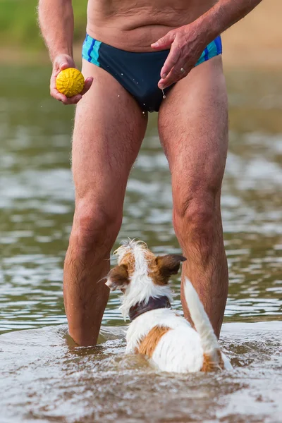 Homme joue avec un chien dans la rivière — Photo