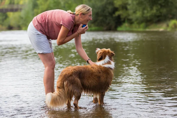 woman plays with a dog in a river