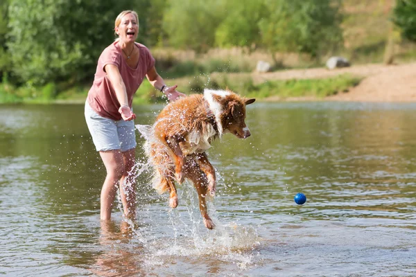 Frau spielt mit Hund in Fluss — Stockfoto