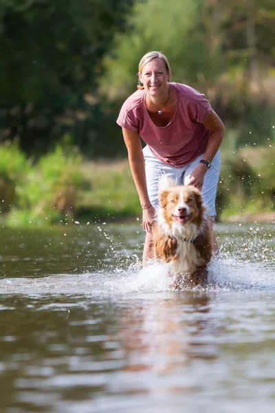 Donna gioca con il suo cane in acqua — Foto Stock