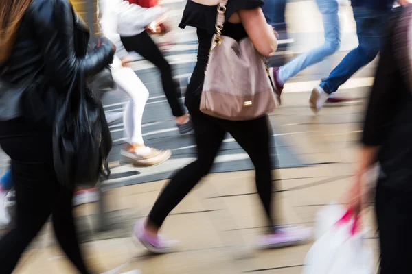 Personas mostradas en movimiento borroso cruzar una calle — Foto de Stock
