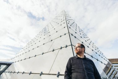 Piramit binanın önünde vizyon arayan genç bir iş adamının resmi.