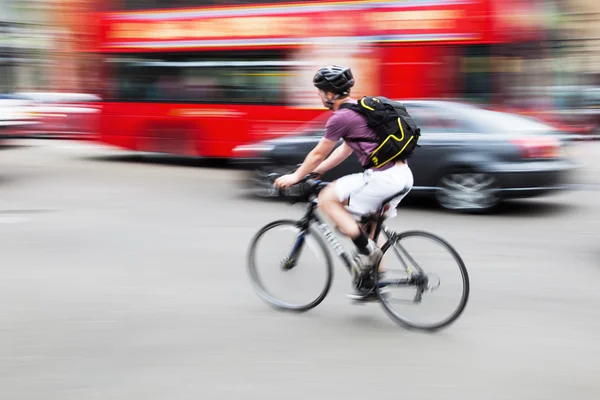 Bicycle rider overtaking a Porsche and a London bus — Stock Photo, Image