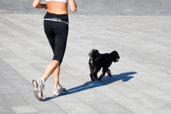 Mulher está correndo com um cão — Fotografia de Stock