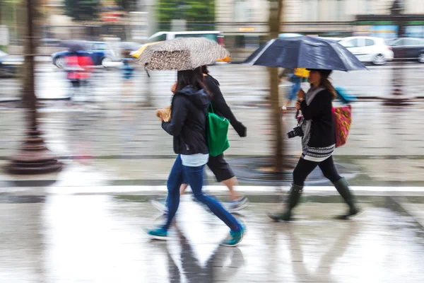 Mensen in beweging vervagen wandelen in de regenachtige stad — Stockfoto