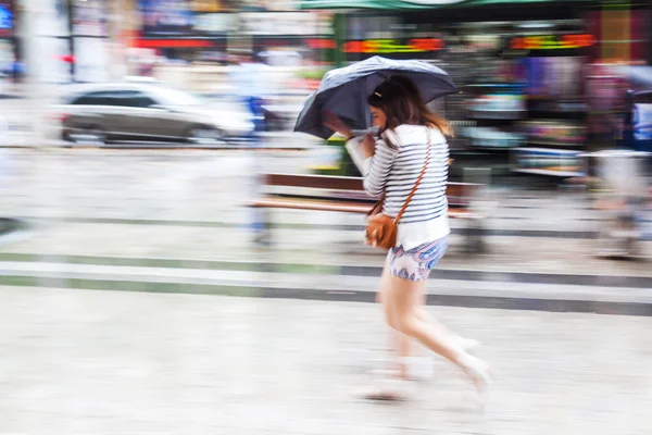 Pessoas em movimento desfocam caminhando na cidade chuvosa — Fotografia de Stock