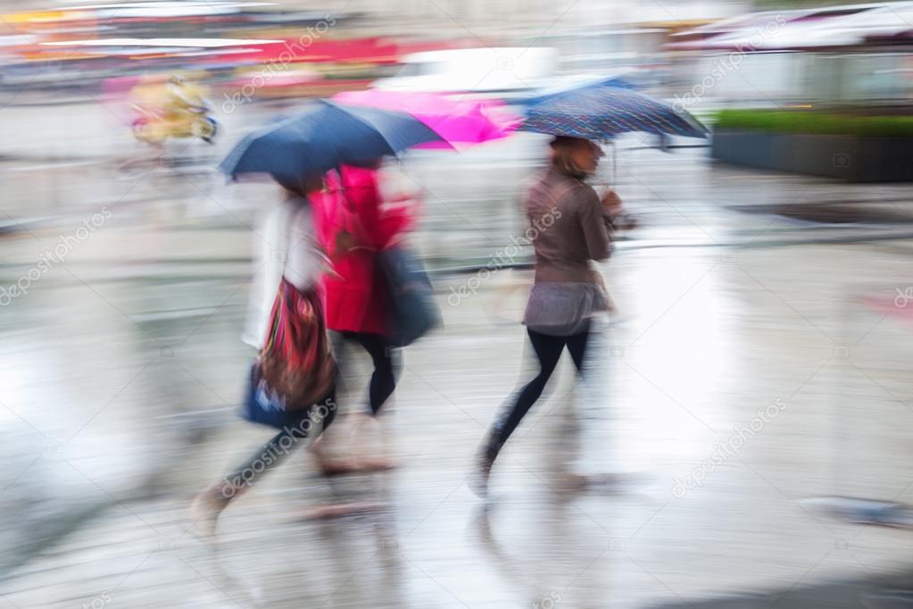 People in motion blur walking in the rainy city