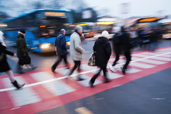 Orang-orang menyeberang jalan di stasiun bus saat fajar — Stok Foto