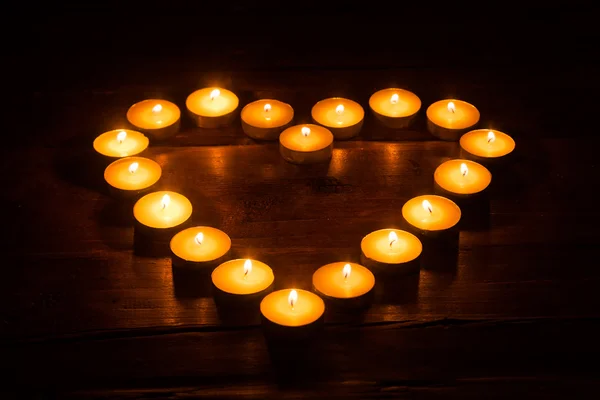 Burning tea lights shaped like a heart in the dark — Stock Photo, Image
