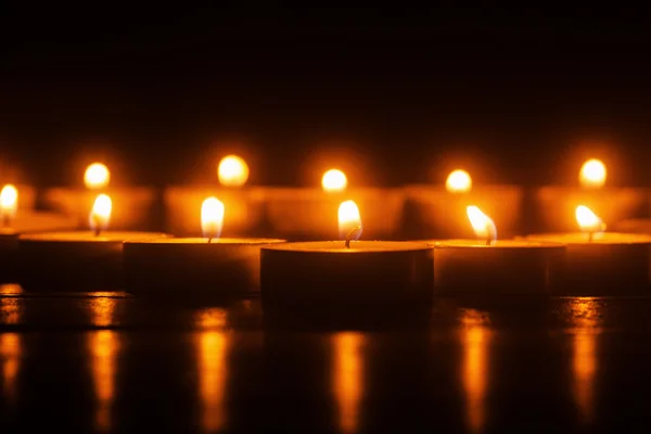 Row of burning tea lights in the dark — Stock Photo, Image