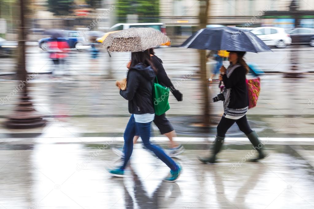 Young people in motion blur walking in the rainy city