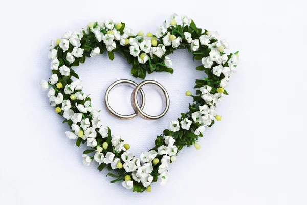 Flower heart with wedding rings — Stock Photo, Image
