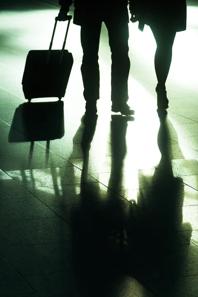 Viajando personas con bolsas de carro en el aeropuerto con retroiluminación —  Fotos de Stock