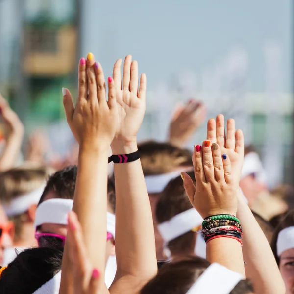 Mani alzate di una folla di persone a un evento sportivo — Foto Stock