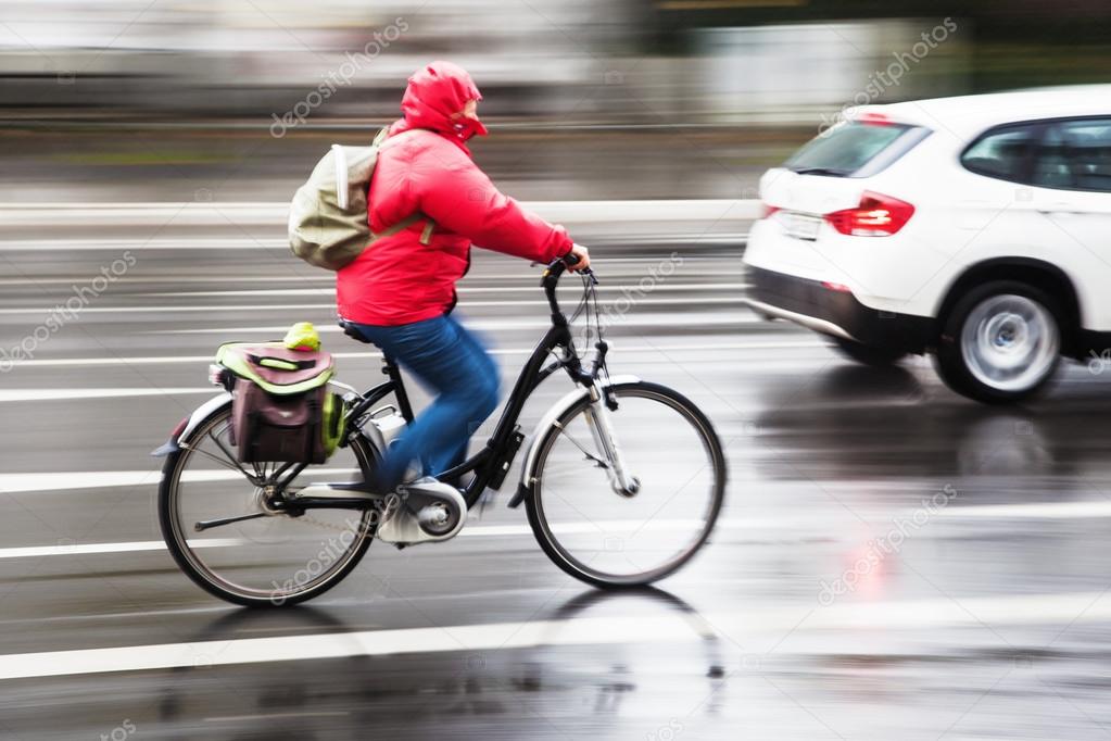 Cyclist in city traffic in motion blur on a rainy day