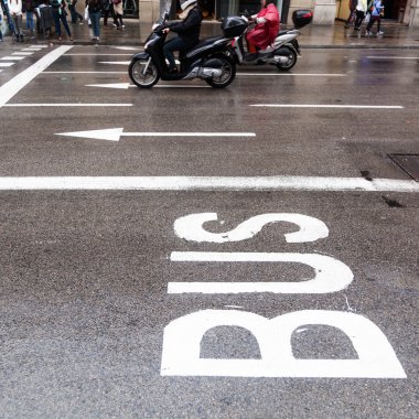 Bus lane of a city street with scooterists in the background clipart