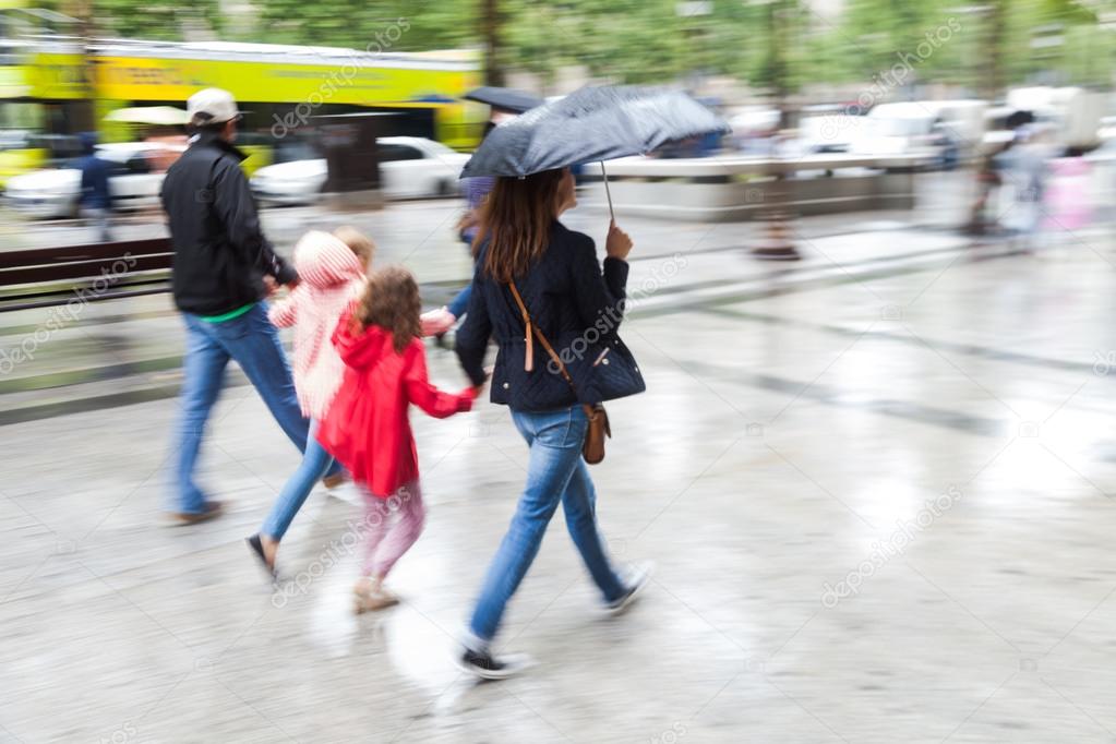 Family in motion blur walking in the rainy city