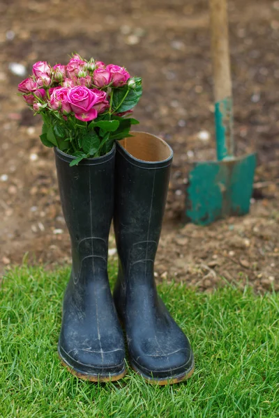 Scène de jardin avec un bouquet de roses en bottes de gomme — Photo
