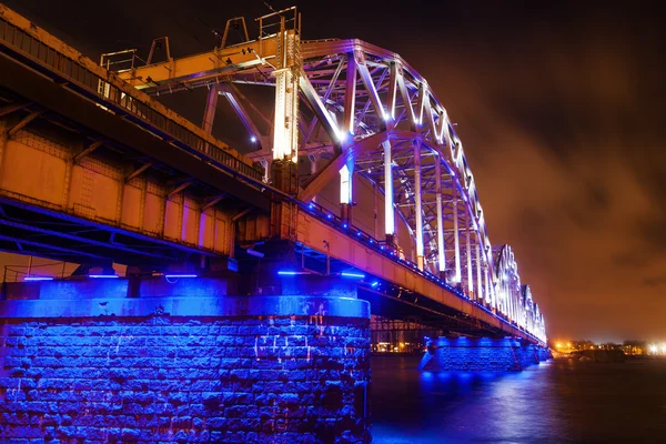 Ponte ferroviária azul iluminada sobre o rio Daugava em Riga, Letónia — Fotografia de Stock