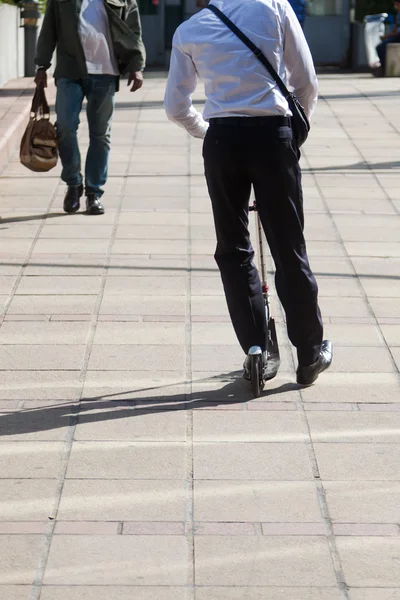 Empresario con una patineta scooter en movimiento en la ciudad —  Fotos de Stock