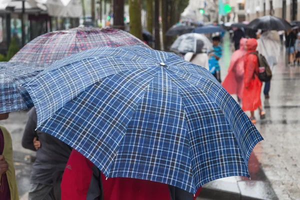 Lidé s rain deštníky v deštivé city — Stock fotografie